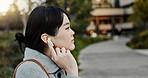 Japanese woman, earphones and walk in city with listening, music and streaming subscription on road. Girl, person and audio tech for podcast, radio and sound with travel on metro sidewalk in Tokyo