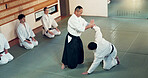 Aikido, class and fight with a master in martial arts with student in self defence, discipline and training. Technique, demonstration or Japanese sensei with black belt skill in fighting or education