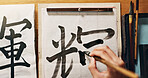 Man, calligraphy or hands of a Japanese artist in studio for art and script, letter with closeup for alphabet. Start, top or male person with tools, paintbrush and focus with traditional stationery