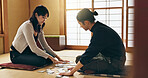 Man, woman and game with Japanese cards on floor in challenge, contest or problem solving with clue. People, couple and karuta for competition with paper, reading or play together to relax in home