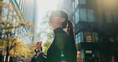 Buy stock photo Japanese woman, phone and earphones in city with smile, walking and listening to music by buildings. Person, pedestrian and smartphone with audio streaming subscription with radio app on metro street