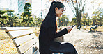 Happy asian woman, phone and typing on park bench for social media, communication or networking. Female person smile in relax on mobile smartphone for online search, streaming or reading in nature