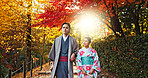 Japanese people in park, walking and traditional clothes with path, nature and sunshine with respect and culture. Couple outdoor together in garden, date or commitment with love, bonding and calm