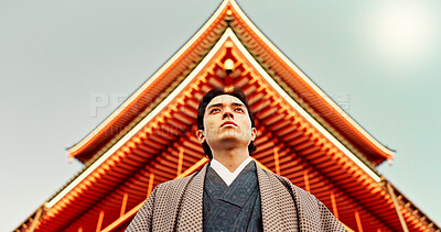 Asian, man at temple in Japan and religion, low angle view for mindfulness, culture and tradition. Worship, peace and walking in traditional clothes outdoor with Japanese architecture and landmark