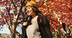 Asian woman, autumn trees and walking in Japan for natural scenery, adventure or journey in nature. Female person smile with backpack or bag for outdoor trip with blooming plants or leaves in season