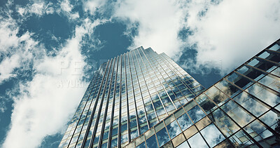 Low angle, skyscraper building and clouds with reflection, nature or urban infrastructure in city. Architecture, cityscape and skyline and metro with landscape, glass and sky background in timelapse