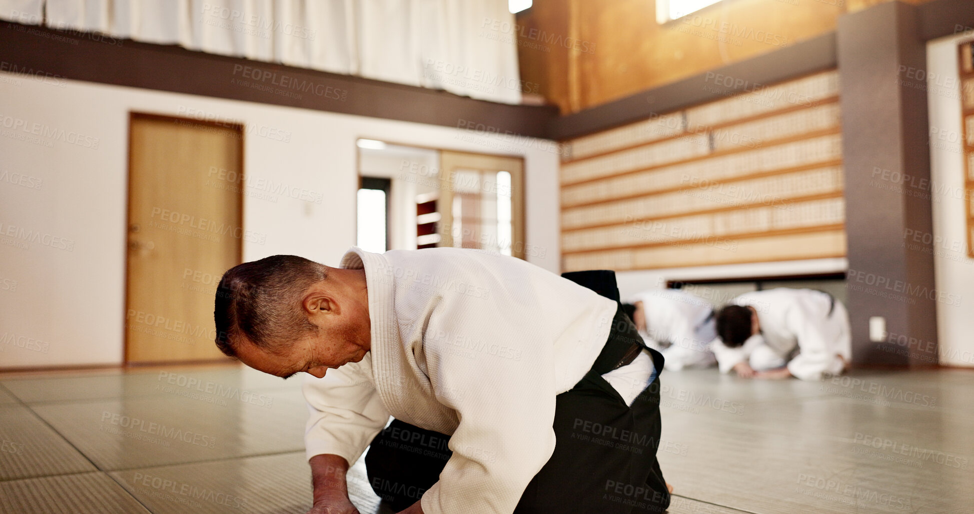 Buy stock photo Aikido class, sensei and students with bow, martial arts or respect for calm at training, gym or dojo. Japanese people, floor and club for exercise, workout and fitness with fight, ready and battle