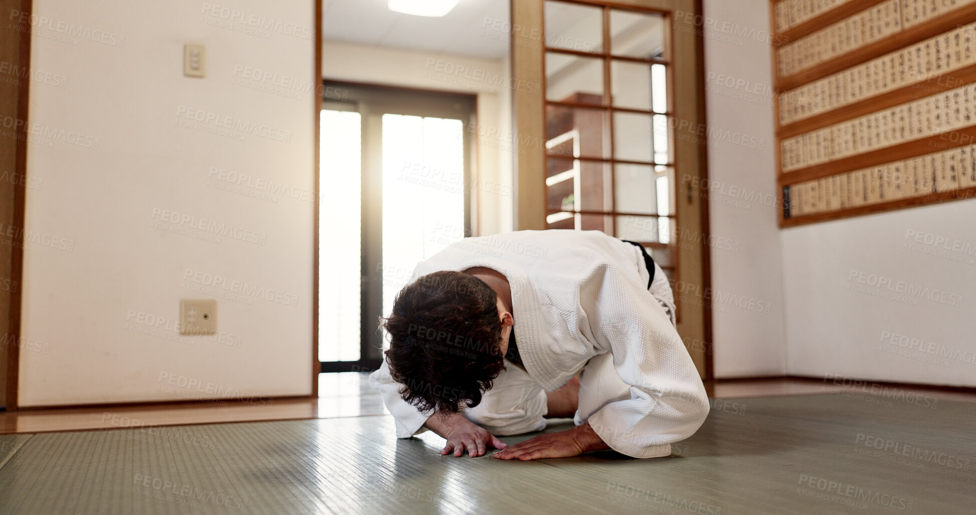 Buy stock photo Aikido student, man or bow in dojo for training practice, discipline and black belt in class. Respect, greeting and Japanese person on floor with traditional gesture, culture and martial arts in gym.