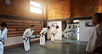 Students, bow or sensei in dojo to start aikido practice, discipline or self defense education. Combat demonstration, Japanese people learning respect or ready for fighting class, training or fitness