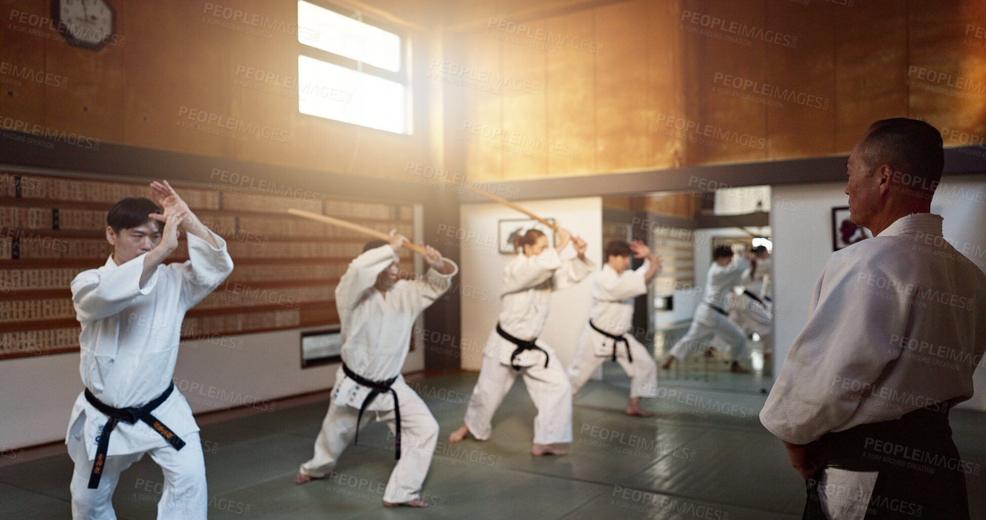Buy stock photo Aikido, group and class with sensei, weapon training and wooden sword for self defence exercise. Dojo, student or athlete in Japanese studio gym with fight challenge, black belt practice and fitness