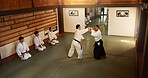 Group of men in dojo with sensei for aikido training, fitness and challenge with action, exercise and coaching. Teaching, learning and students in traditional Japanese martial arts class with mentor.