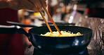 Cooking, restaurant and person with noodles in pan on gas stove at market for meal preparation, eating and cuisine. Culinary, flame and closeup of chopsticks to prepare lunch, dinner and supper