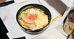 Ramen food, plate and table in restaurant with person, hands and ginger with closeup for Japanese cuisine. Niboshi bowl, chopsticks and pork for diet, nutrition and catering for wellness in Tokyo