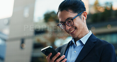 Buy stock photo Phone, smile and Japanese businessman in the city reading company email on technology. Happy, career and professional young male person scroll or browse on cellphone with earbuds in urban town.