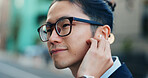 Business man, city and listening to music, digital podcast and streaming audio connection with earphones. Face, Japanese employee and thinking of sound for radio subscription in urban street in Tokyo