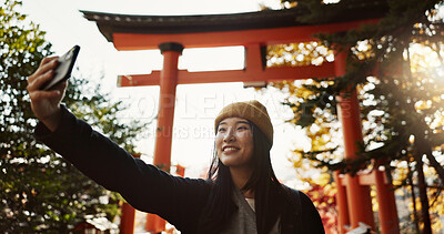 Buy stock photo Selfie, smile and Japanese woman at shrine in forest for holiday adventure at Torri gate in Japan. Happy in woods, trees and girl with digital photography, social media and live stream on travel blog
