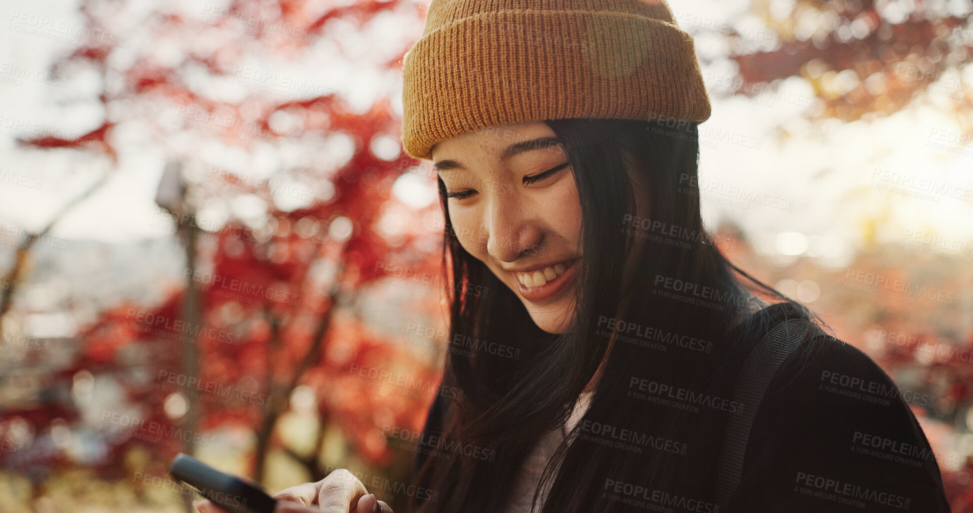 Buy stock photo Phone, nature and Japanese woman in forest for holiday, vacation and adventure in Japan. Happy smile, autumn leaves and girl with smartphone for online search, social media post or memories for blog.
