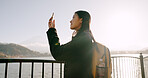 Japanese woman, lake and phone for photography, memory and post on web blog for travel with backpack. Girl, person and outdoor with smartphone by water, river and photoshoot for social media in Tokyo