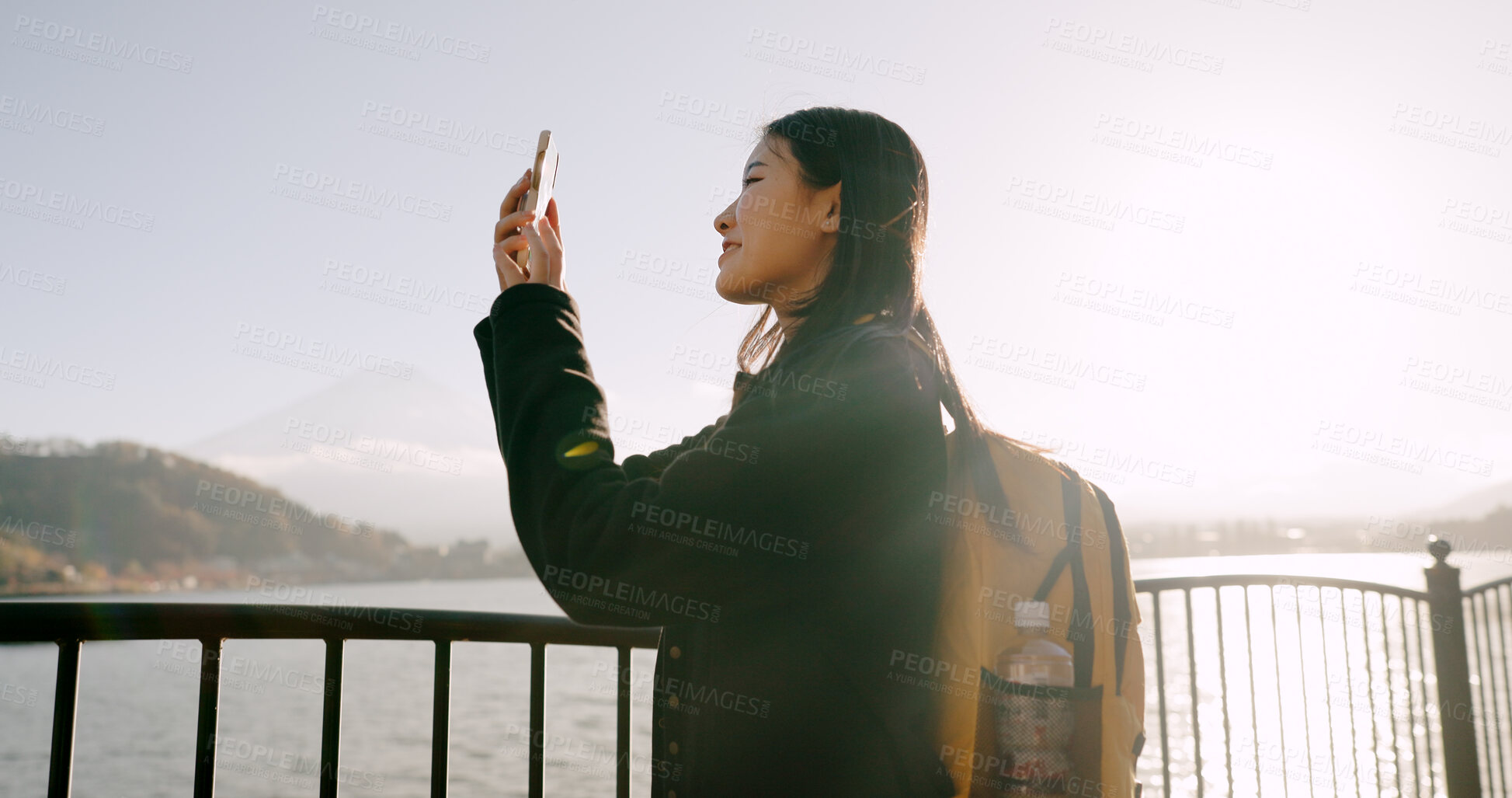 Buy stock photo Japanese woman, lake and phone for photography, memory and post on web blog for travel with backpack. Girl, person and outdoor with smartphone by water, river and photoshoot for social media in Tokyo