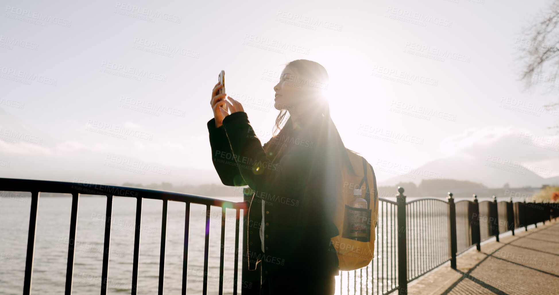 Buy stock photo Japanese woman, lake and phone for photography, memory and post on web blog for travel with backpack. Girl, person and outdoor with smartphone by water, river and photoshoot for social media in Tokyo