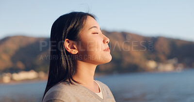 Japanese woman, breathing and peace outdoor, lake or ocean with travel, holiday and mindfulness in nature. Wellness, adventure and care free at beach in Japan, calm with freedom and positivity