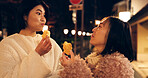 Woman, friends and street food or eating Japanese snack for travel experience, hungry or local trip. Female people, sidewalk and night walk on vacation for nutrition culture, adventure or traditional