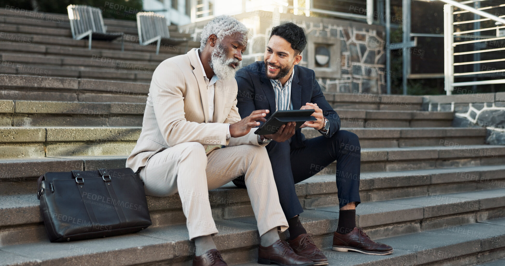 Buy stock photo Tablet, conversation and business men in the city in discussion for corporate legal case. Teamwork, collaboration and male attorneys with digital technology sitting and talking on stairs in town.