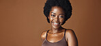 Face of black woman, afro model or natural beauty for wellness, cosmetics or healthy skin in studio. Dermatology, pride or serious African person with glow or skincare results on brown background