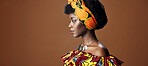 Culture, African fashion or face of black woman in studio on a brown background for trendy style. Unique, beauty or model with confidence, pride or afro posing in wrap, clothes or traditional outfit