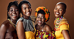 Traditional African women, group and studio for face, jewelry or beads necklace in clothes by brown background. Black people, model and indigenous fashion for friends, culture or portrait for kwanzaa