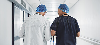 Doctor, nurse and talk while walk in hospital with advice, consult or communication with medical team. People, discuss or coaching for patient care, treatment and wellness after surgery with joke