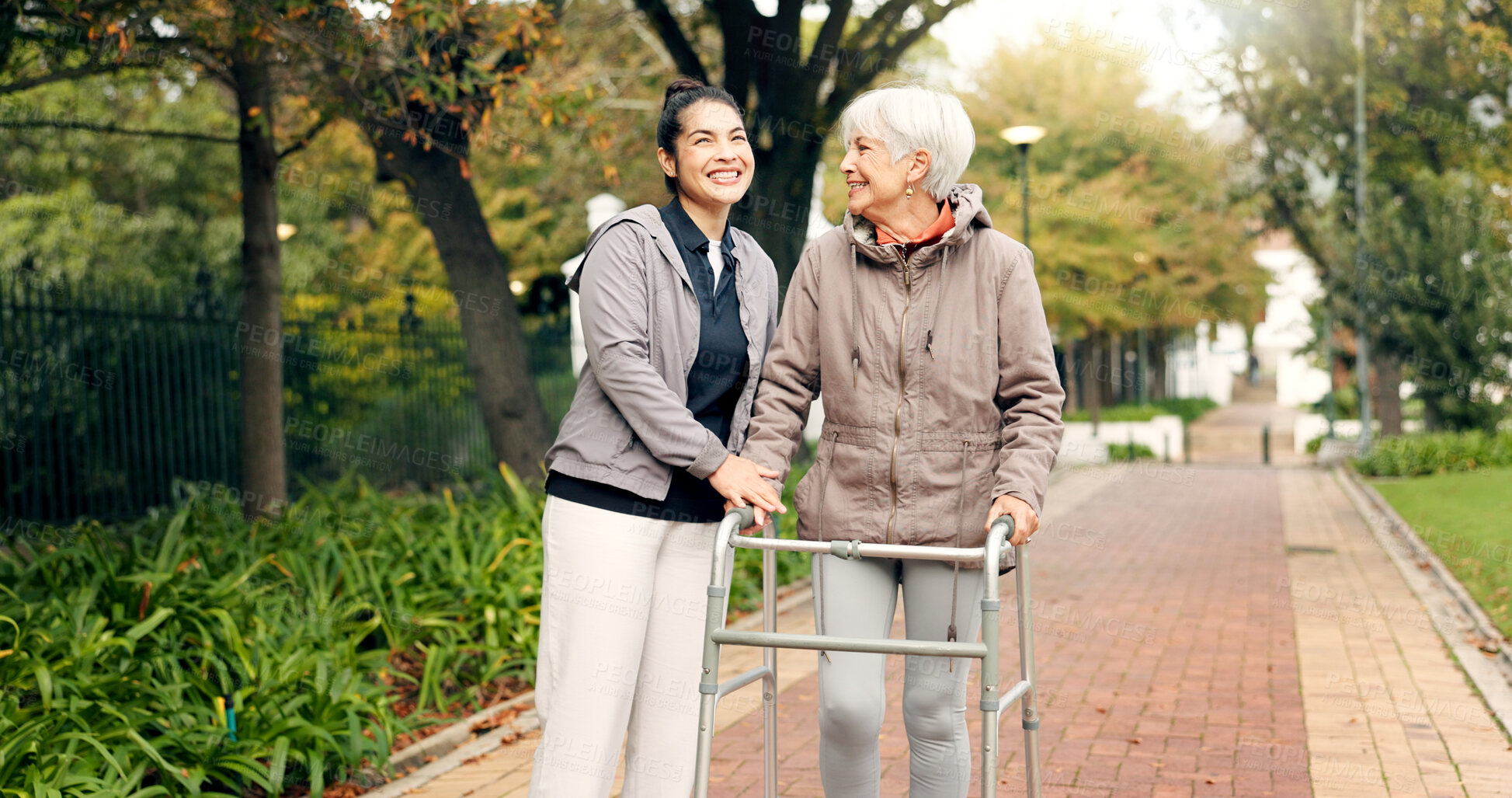 Buy stock photo Senior woman, walker and nurse outdoor in a park with healthcare for elderly exercise. Walking, healthcare professional and female person with peace and physical therapy in a public garden with carer