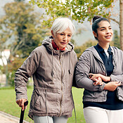 Senior woman, walker and nurse talking in a park with healthcare for ...