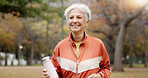 Fitness, senior woman and walking at park for healthy body, wellness or exercise with bottle. Smile, workout and elderly athlete outdoor, nature or garden for cardio, sport and travel for retirement