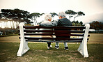 Hug, bench or old couple in park or nature talking or bonding together in retirement outdoors back view. Senior, elderly man or mature woman on date to relax with love, peace or care on calm holiday