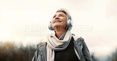 Headphones, music and senior woman in nature for wellness, mental health and happy outdoor experience. Travel, listening and streaming service or podcast of elderly person thinking in park and winter