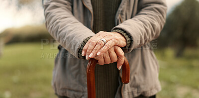 Senior cane, hands and person in nature for walking, relax and in a park for peace. Closeup, standing and an elderly woman in a garden or natural environment for wellness with a stick for support