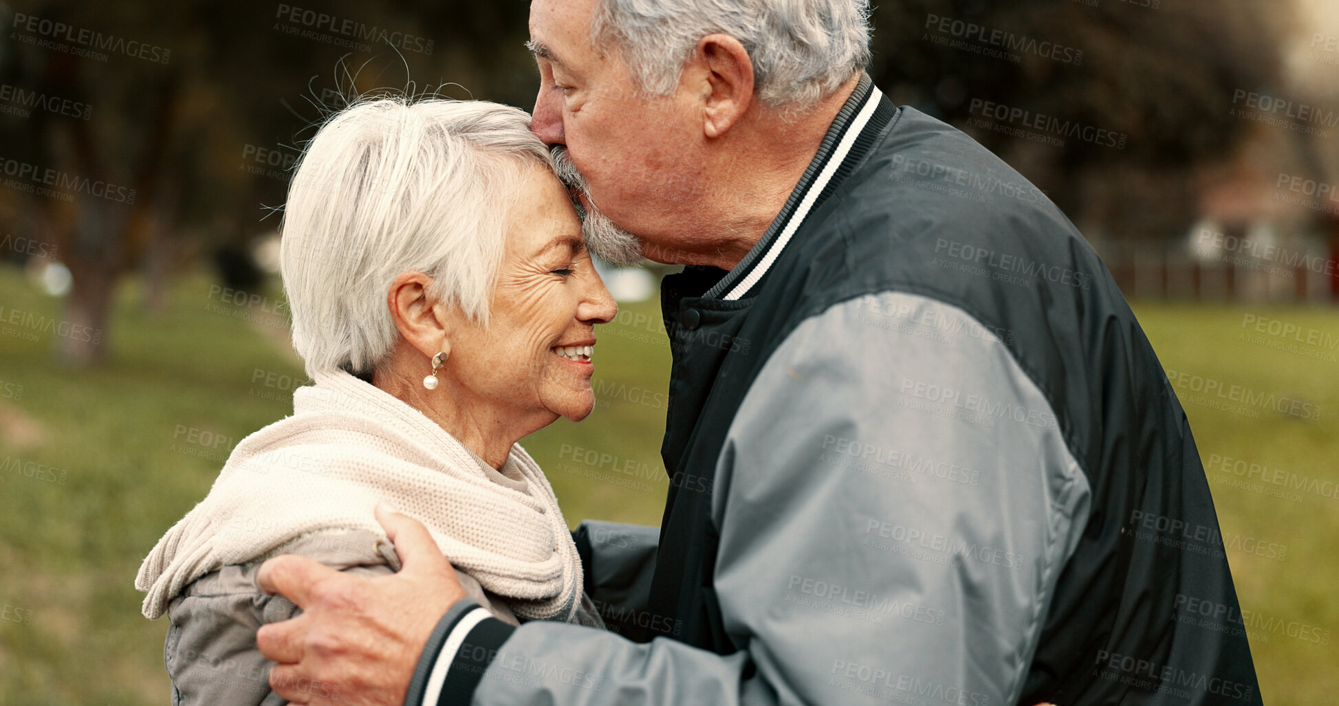Buy stock photo Love, smile and kiss with a senior couple hugging outdoor in a park together for a romantic date during retirement. Happy, support and an elderly man and woman bonding in a garden for romance