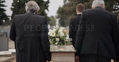 Men, coffin and pallbearers walking at cemetery ceremony outdoor at burial tomb. Death, grief and group casket at funeral, carry to graveyard and family service of people mourning at windy event.