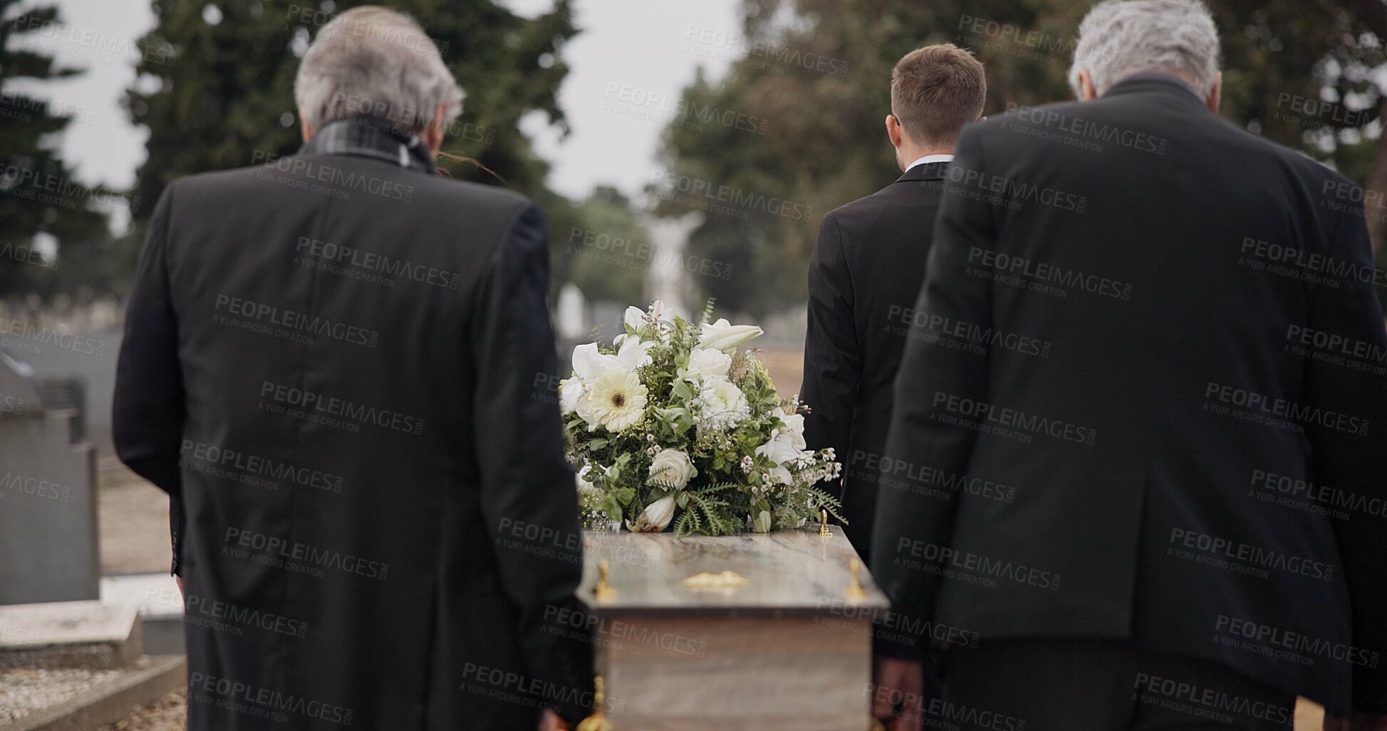 Buy stock photo Men, coffin and pallbearers walking at cemetery ceremony outdoor at burial tomb. Death, grief and group casket at funeral, carry to graveyard and family service of people mourning at windy event.