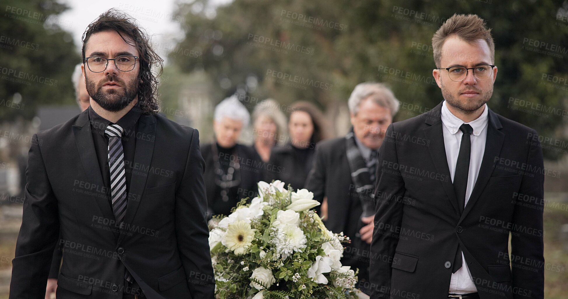 Buy stock photo Pallbearers, men and walking with coffin at graveyard ceremony outdoor at burial place. Death, grief and group of people with casket at cemetery for funeral and family service while mourning at event