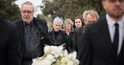 Pallbearers, men and walking with coffin in funeral, ceremony or mourning event at graveyard with sad, grief and flowers. People, support and walk with family in memorial service together with casket