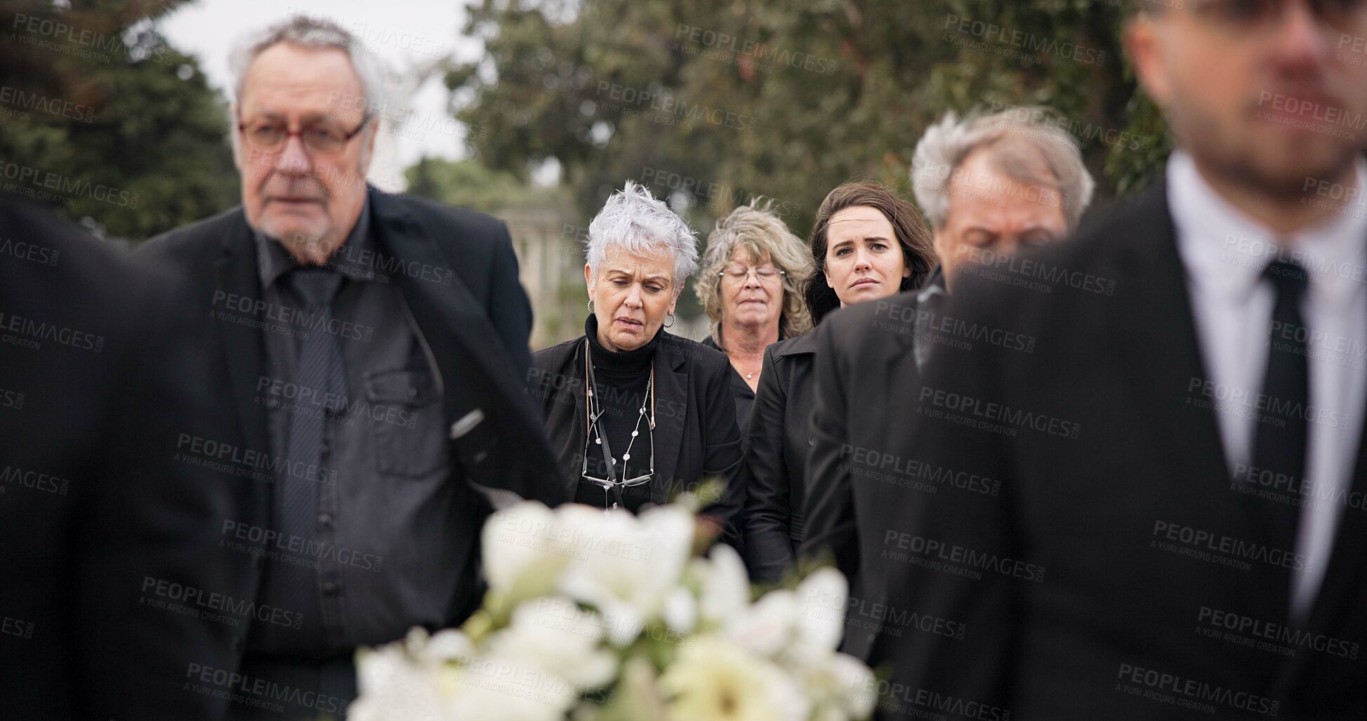 Buy stock photo Pallbearers, men and walking with coffin in funeral, ceremony or mourning event at graveyard with sad, grief and flowers. People, support and walk with family in memorial service together with casket