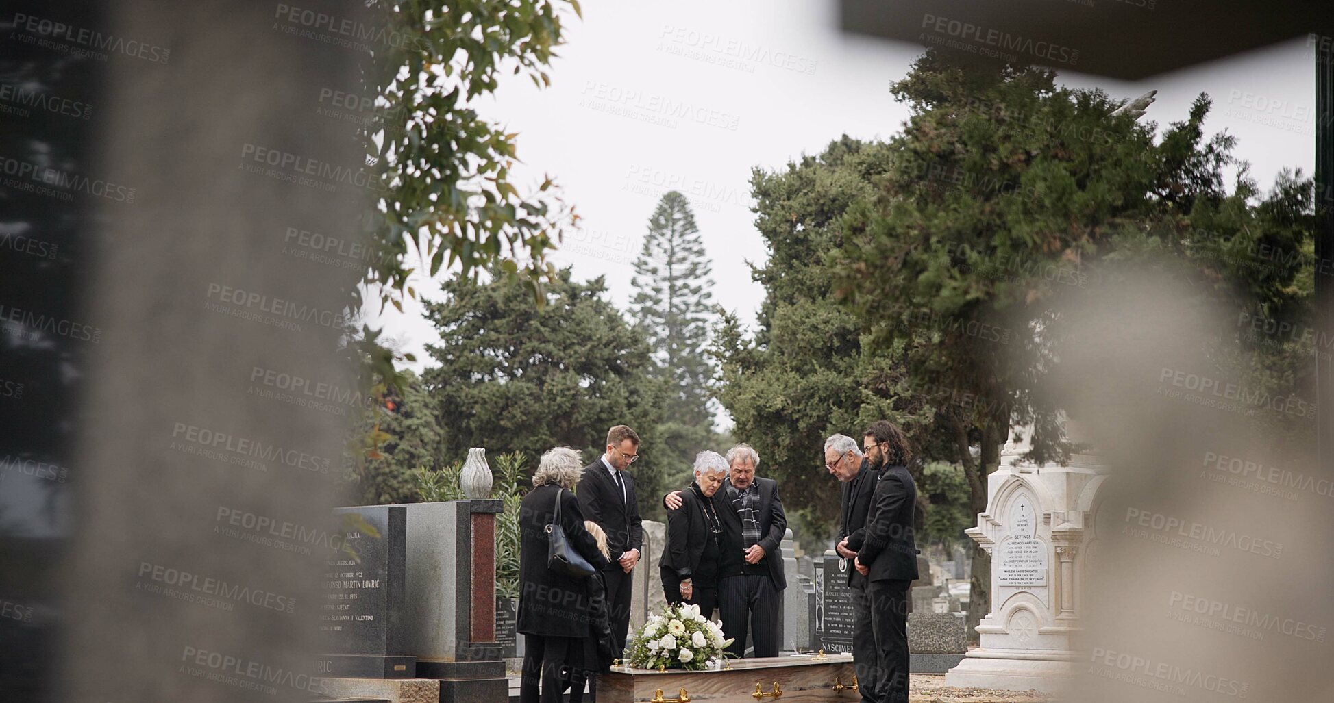 Buy stock photo People at a funeral, death and graveyard with family mourning outdoor, grief and loss with coffin. Cemetery, ceremony and sad, goodbye and burial service with support, comfort and empathy at memorial