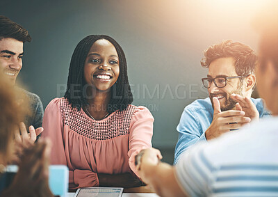 Buy stock photo Shot of two businesspeople shaking hands while their colleagues applaud in an office