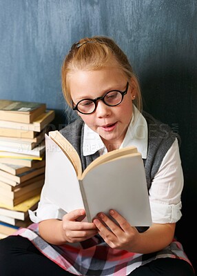 Buy stock photo Child, student reading book and chalkboard for education, language learning and knowledge in classroom. Smart girl or storytelling in glasses and school library, creative development and literature