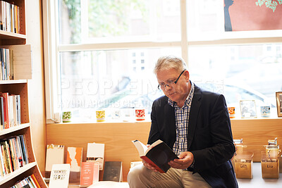 Buy stock photo Senior man, library and reading book for literature, knowledge or story at bookstore. Mature male person, author or bookworm sitting by bookshelf for novel, learning or wisdom in shopping or leisure