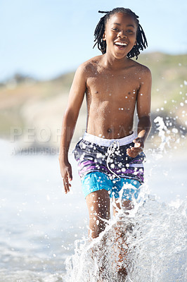 Buy stock photo Portrait, African boy and happiness on beach in water for adventure, holiday or vacation in summer. Happy kid, face and smile outdoor in nature for break, experience or playing in ocean with splash