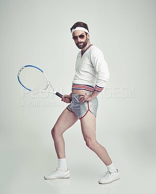 Buy stock photo A young man in the studio wearing ill-fitting retro tennis wear and shades while holding a racquet