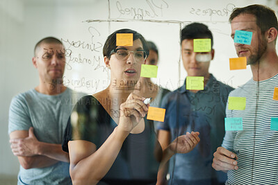 Buy stock photo Designers planning a strategy for a group project on a glass whiteboard together in a meeting. Creative, confident and professional young men and women writing smart ideas down together as a team